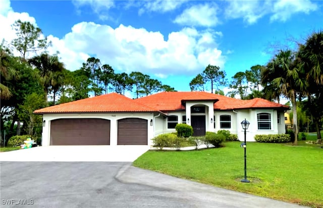 mediterranean / spanish-style home featuring a front lawn and a garage