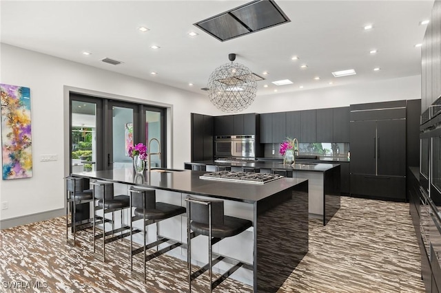 kitchen featuring a kitchen bar, appliances with stainless steel finishes, tasteful backsplash, sink, and a large island