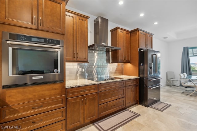 kitchen with light stone countertops, backsplash, wall chimney exhaust hood, and black appliances