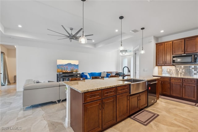 kitchen with decorative backsplash, appliances with stainless steel finishes, a raised ceiling, sink, and a center island with sink