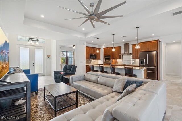 living room featuring french doors, a raised ceiling, and ceiling fan