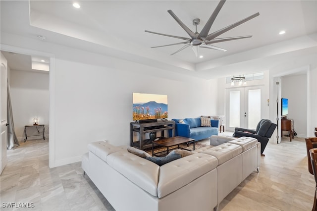 living room featuring a raised ceiling, ceiling fan, and french doors