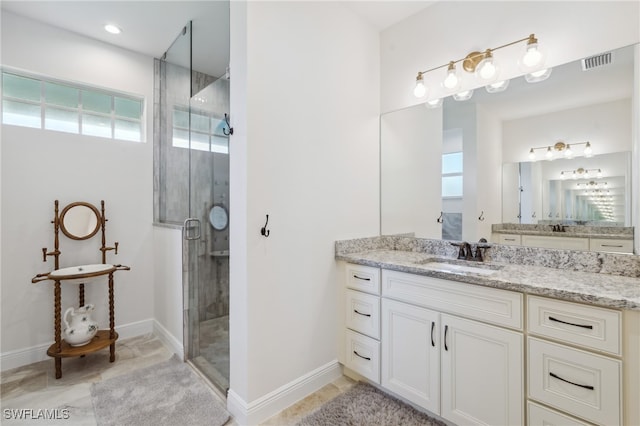 bathroom featuring vanity, a shower with shower door, and a healthy amount of sunlight