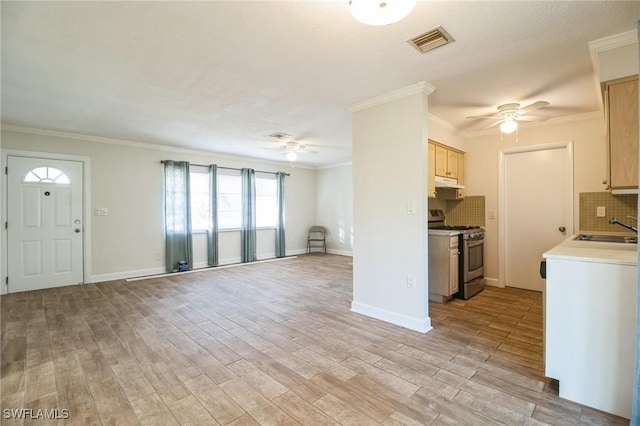 kitchen featuring decorative backsplash, light wood-type flooring, stainless steel range, crown molding, and sink