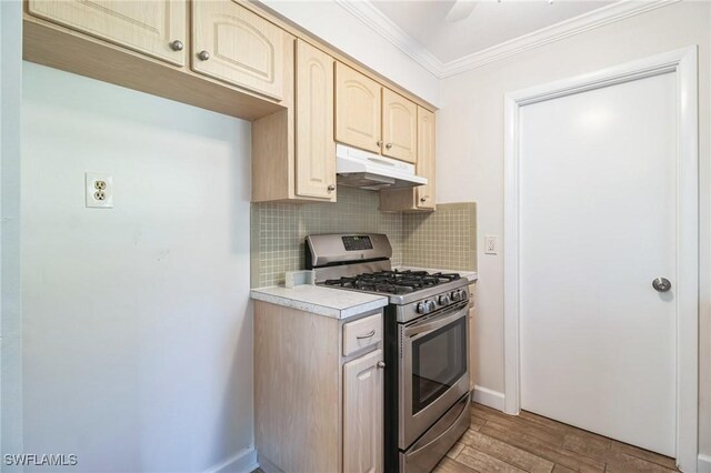 kitchen featuring decorative backsplash, ornamental molding, light brown cabinetry, light hardwood / wood-style floors, and stainless steel range with gas stovetop