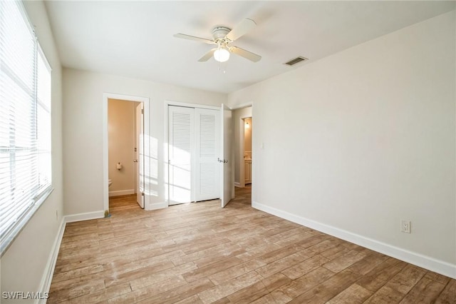 unfurnished bedroom with ensuite bathroom, light wood-type flooring, and multiple windows