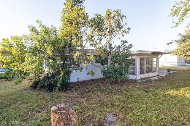 view of side of property featuring a sunroom and a lawn