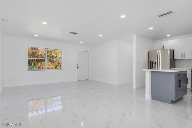 kitchen featuring white cabinetry, gray cabinets, a kitchen island, and stainless steel fridge