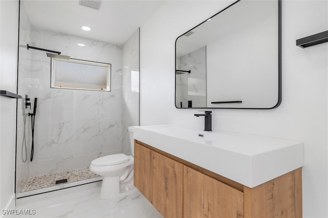 bathroom with vanity, toilet, and a tile shower