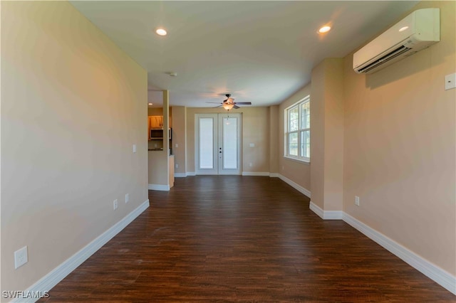 spare room with an AC wall unit, french doors, ceiling fan, and dark hardwood / wood-style flooring