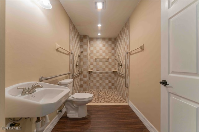 bathroom with sink, a tile shower, hardwood / wood-style flooring, and toilet