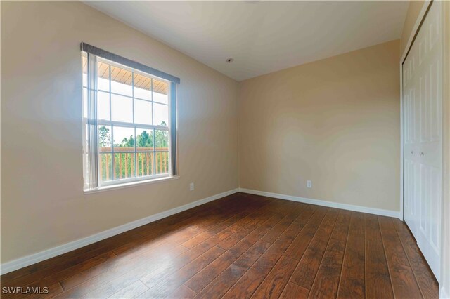 unfurnished bedroom with multiple windows, a closet, and dark hardwood / wood-style flooring