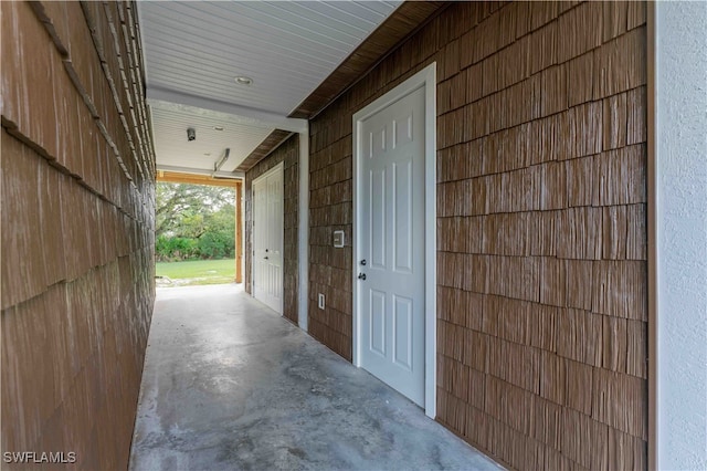 hallway featuring wooden walls and concrete flooring