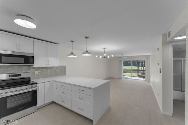 kitchen with appliances with stainless steel finishes, kitchen peninsula, white cabinets, and tasteful backsplash