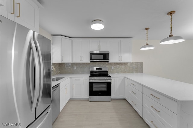 kitchen with decorative backsplash, hanging light fixtures, white cabinetry, sink, and stainless steel appliances