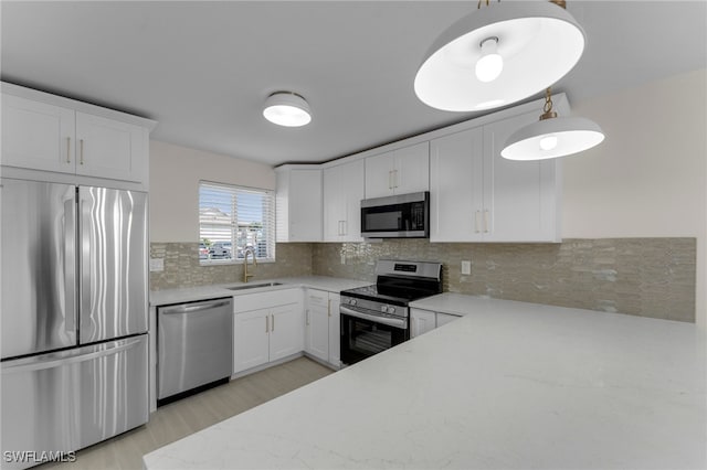 kitchen featuring tasteful backsplash, appliances with stainless steel finishes, sink, white cabinets, and light hardwood / wood-style flooring