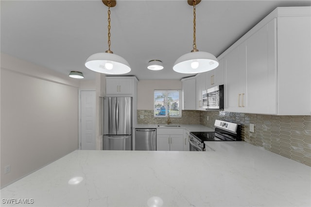 kitchen featuring white cabinets, tasteful backsplash, sink, pendant lighting, and stainless steel appliances