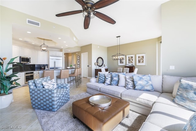 tiled living room featuring ceiling fan with notable chandelier