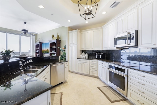 kitchen with pendant lighting, white cabinets, sink, dark stone countertops, and stainless steel appliances