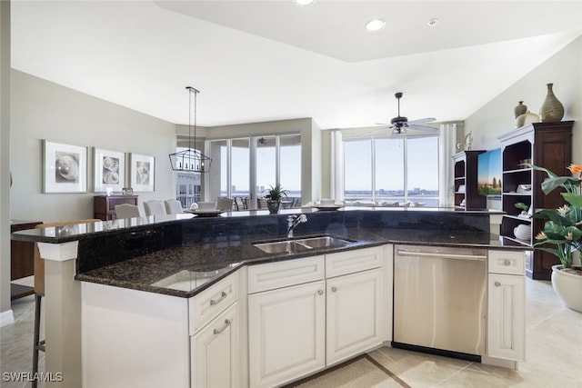 kitchen with dark stone counters, a kitchen breakfast bar, sink, stainless steel dishwasher, and ceiling fan