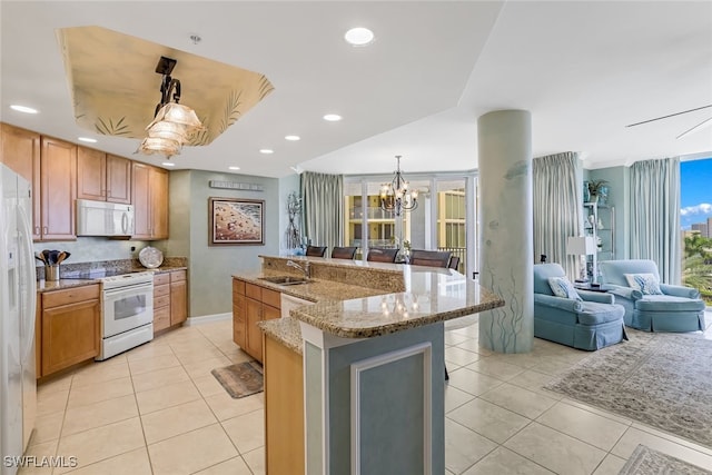 kitchen with a large island, sink, an inviting chandelier, pendant lighting, and white appliances