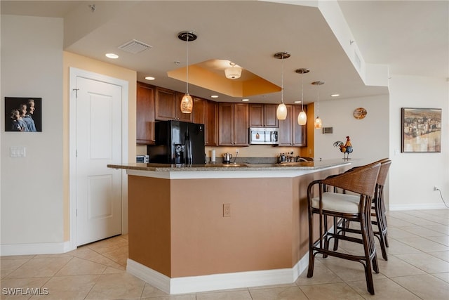 kitchen with hanging light fixtures, black fridge, kitchen peninsula, a breakfast bar area, and light tile patterned floors