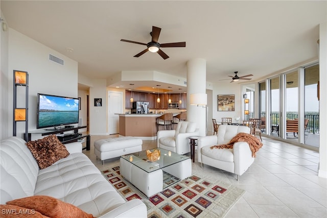 tiled living room featuring expansive windows and ceiling fan