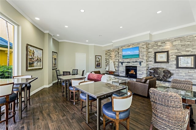 dining area featuring crown molding, a stone fireplace, and dark hardwood / wood-style flooring