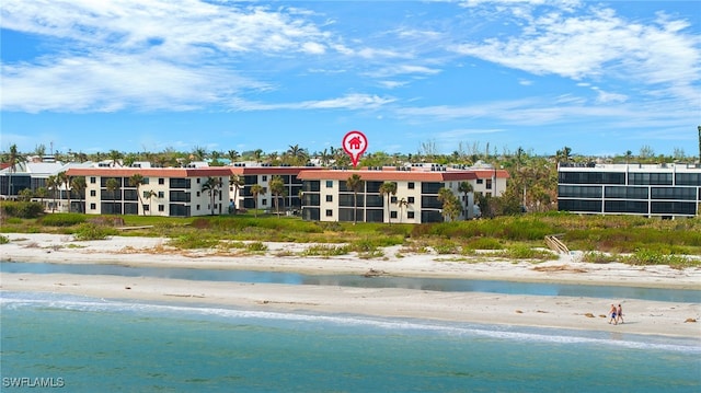 view of building exterior featuring a beach view and a water view