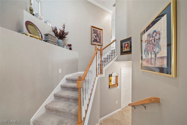 stairway with crown molding and a high ceiling