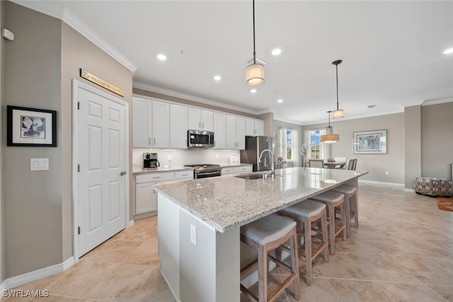 kitchen featuring an island with sink, appliances with stainless steel finishes, white cabinetry, a kitchen bar, and decorative light fixtures