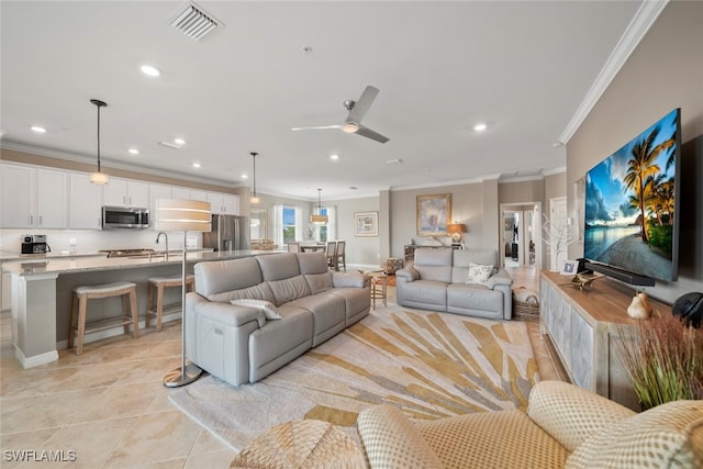 living room featuring ornamental molding, sink, light tile patterned floors, and ceiling fan