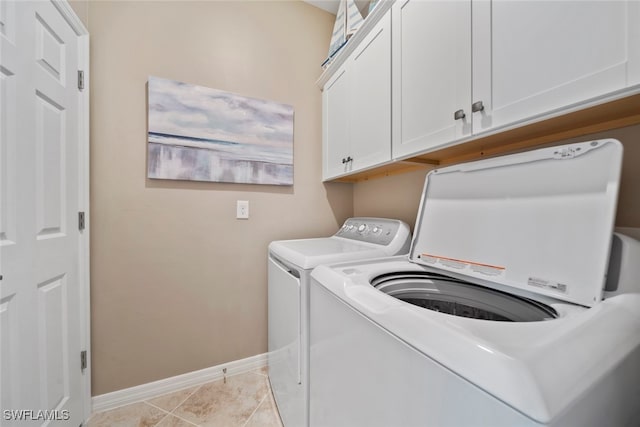 washroom with light tile patterned floors, cabinets, and washer and clothes dryer