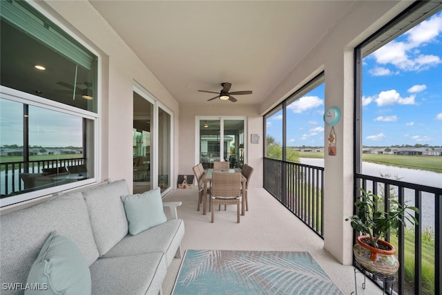 sunroom / solarium with a water view and ceiling fan