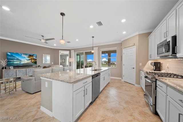 kitchen featuring decorative backsplash, appliances with stainless steel finishes, white cabinets, and an island with sink