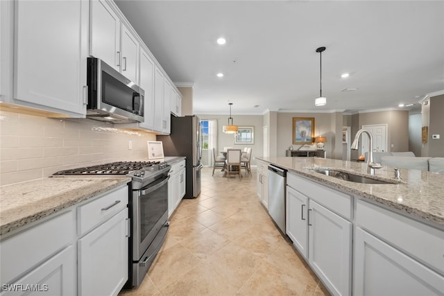 kitchen featuring appliances with stainless steel finishes, white cabinetry, ornamental molding, decorative light fixtures, and sink