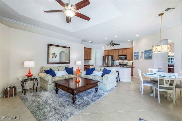 tiled living room with ornamental molding and ceiling fan