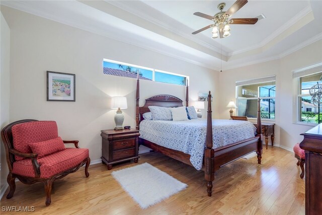 bedroom featuring ornamental molding, hardwood / wood-style flooring, a raised ceiling, and ceiling fan