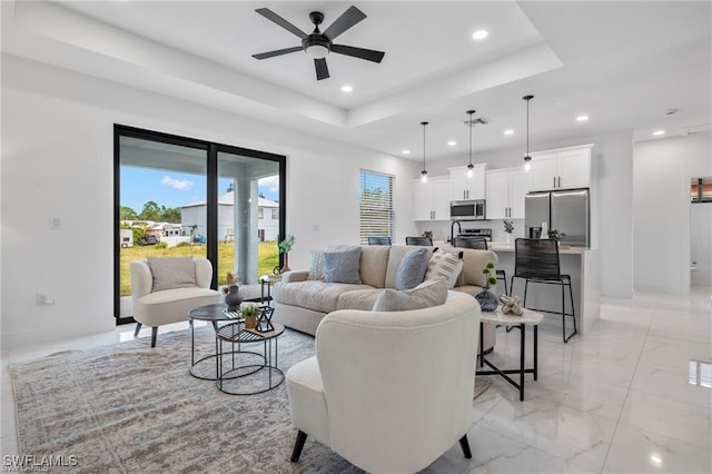 living room with ceiling fan and a raised ceiling