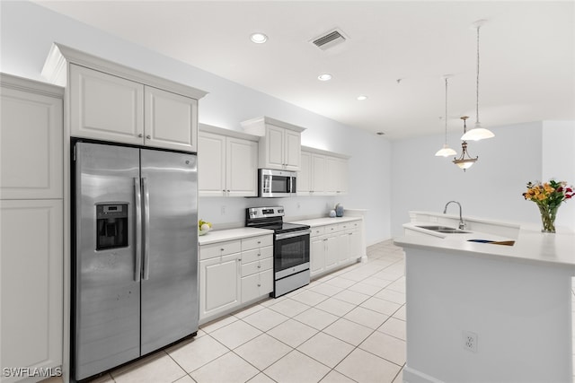 kitchen featuring appliances with stainless steel finishes, white cabinetry, light tile patterned flooring, pendant lighting, and sink