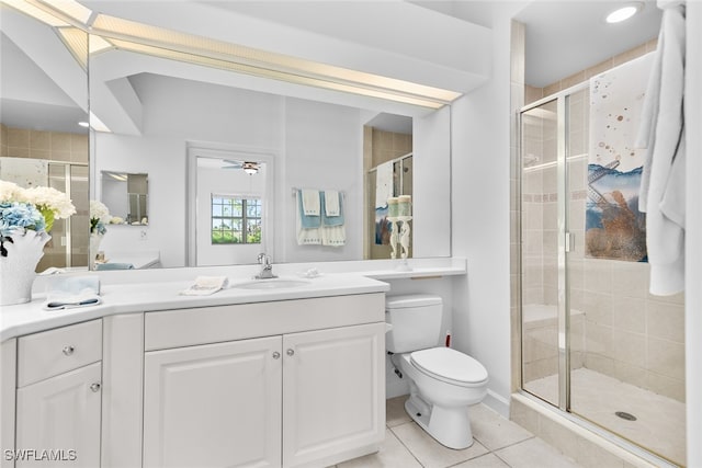 bathroom featuring a shower with door, toilet, ceiling fan, vanity, and tile patterned flooring