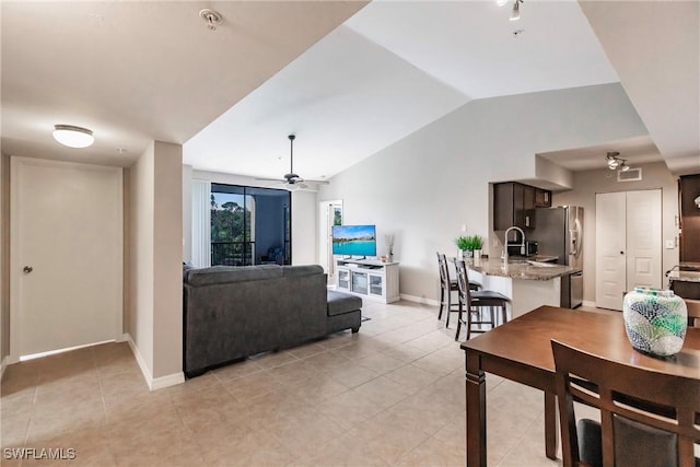 living room with ceiling fan, vaulted ceiling, and light tile patterned floors