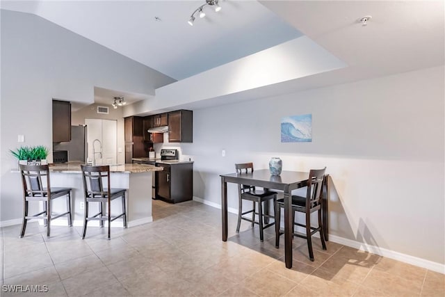 kitchen featuring dark brown cabinetry, lofted ceiling, a kitchen breakfast bar, kitchen peninsula, and stainless steel appliances