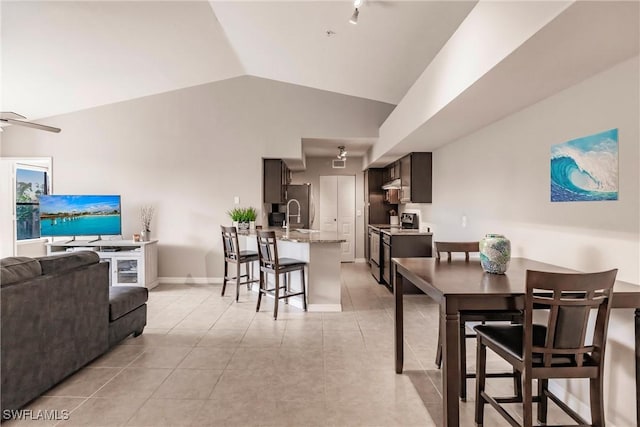 dining room featuring light tile patterned flooring, ceiling fan, sink, and vaulted ceiling