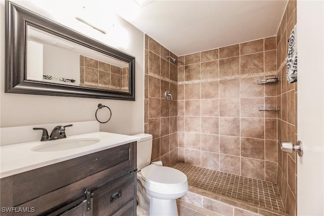 bathroom with vanity, tiled shower, and toilet