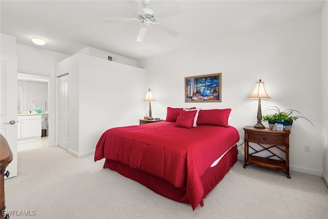 bedroom featuring ensuite bath, light colored carpet, and ceiling fan