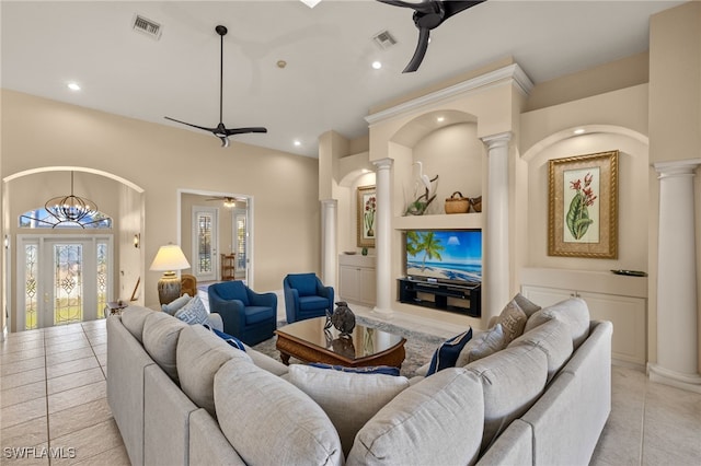 tiled living room with ornate columns and ceiling fan with notable chandelier