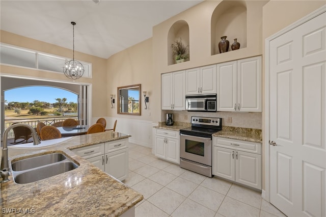 kitchen featuring light stone counters, stainless steel appliances, sink, pendant lighting, and white cabinetry