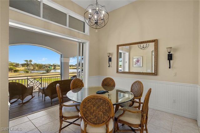 dining area with a water view, light tile patterned floors, and an inviting chandelier