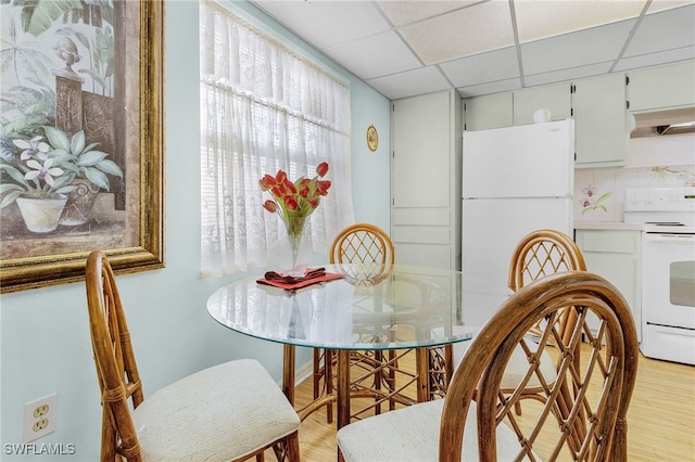 dining area with a drop ceiling and light hardwood / wood-style floors